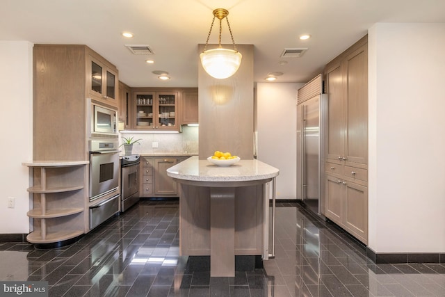 kitchen with tasteful backsplash, a center island, decorative light fixtures, built in appliances, and dark tile floors