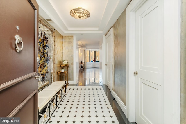 hall with dark tile flooring and a tray ceiling