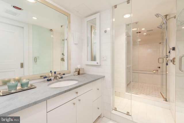 bathroom with vanity, a shower with shower door, and tile walls