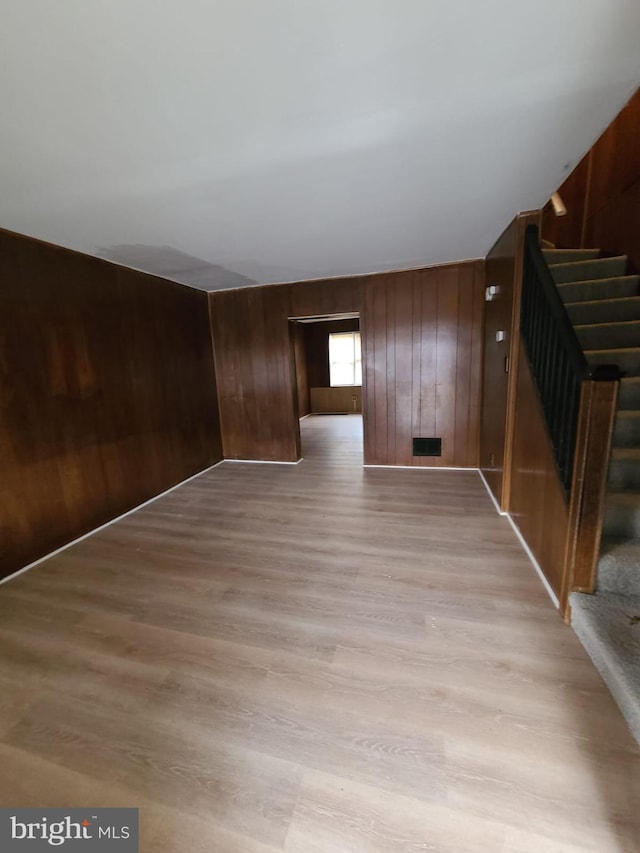 unfurnished room with wood walls and light hardwood / wood-style floors