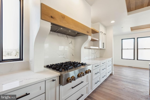 kitchen featuring stainless steel gas stovetop, light hardwood / wood-style flooring, decorative backsplash, light stone countertops, and white cabinetry