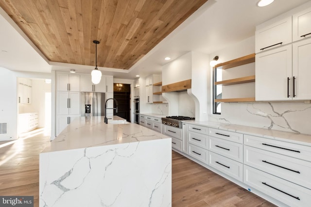 kitchen featuring white cabinets, light hardwood / wood-style floors, and a kitchen island with sink