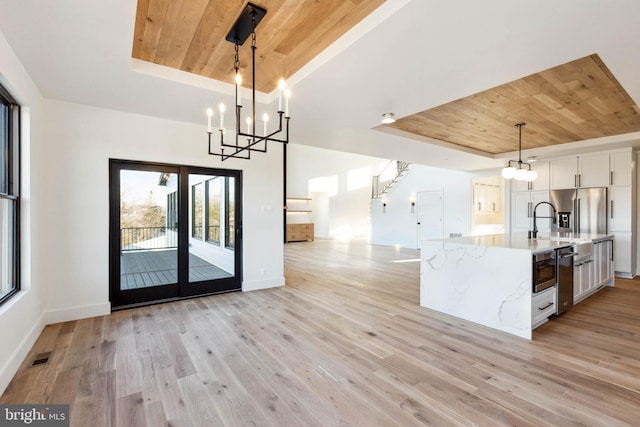 kitchen featuring white cabinets, pendant lighting, light wood-type flooring, and a tray ceiling