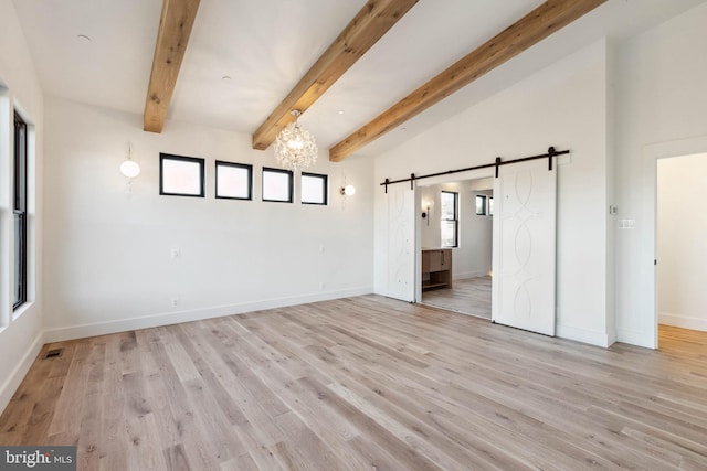 spare room with a barn door, an inviting chandelier, lofted ceiling with beams, and light wood-type flooring