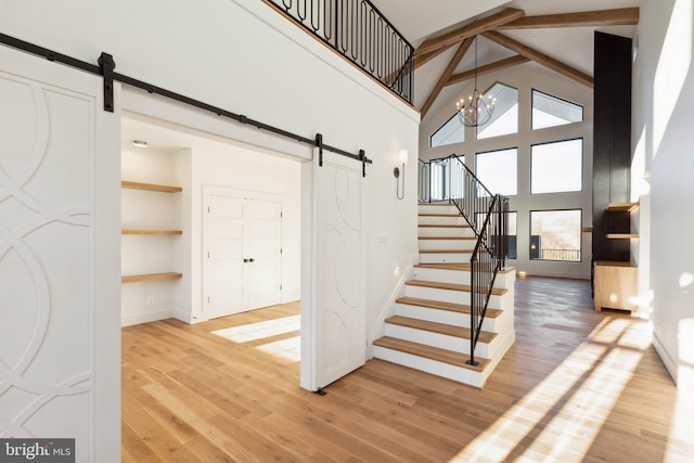 staircase with plenty of natural light, a barn door, and high vaulted ceiling