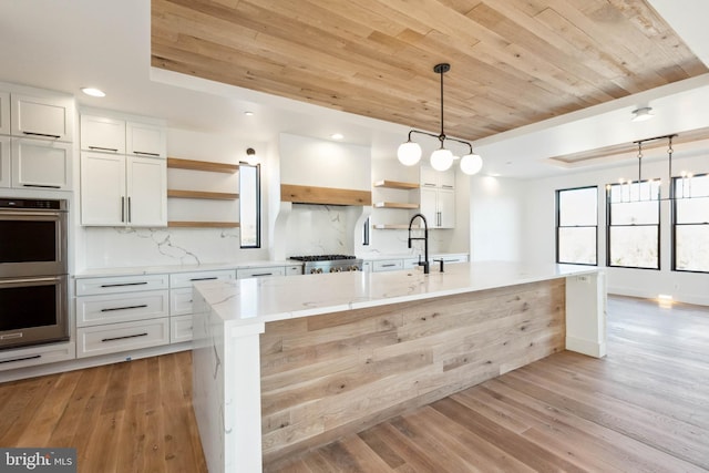 kitchen featuring a center island with sink, white cabinetry, and light hardwood / wood-style flooring