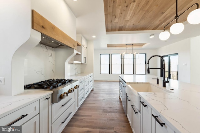 kitchen featuring light stone countertops, stainless steel gas cooktop, dark wood-type flooring, decorative light fixtures, and white cabinetry