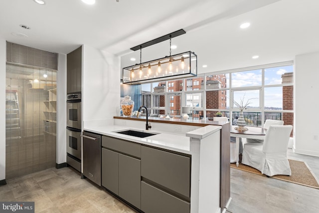 kitchen featuring kitchen peninsula, stainless steel appliances, sink, pendant lighting, and gray cabinets