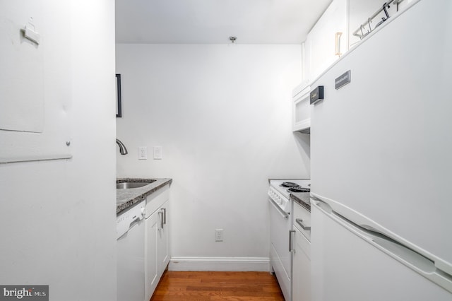 kitchen with white cabinets, white appliances, sink, and hardwood / wood-style floors