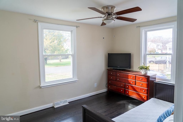 bedroom featuring multiple windows, dark hardwood / wood-style floors, and ceiling fan