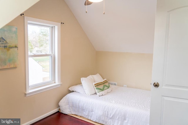 bedroom with multiple windows, ceiling fan, hardwood / wood-style floors, and vaulted ceiling