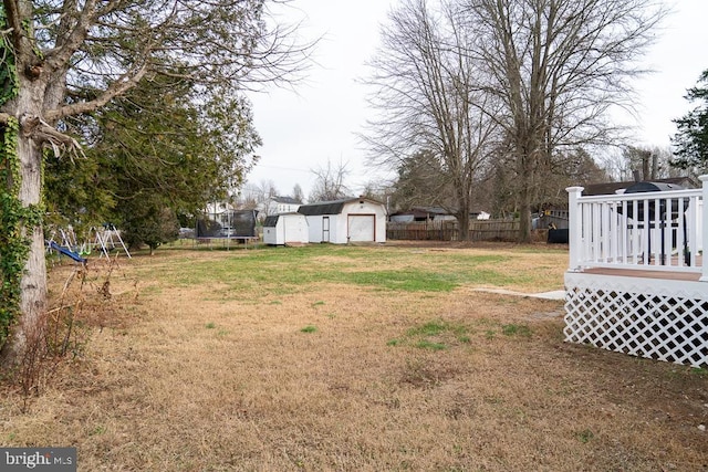 view of yard featuring an outdoor structure, a deck, and a trampoline