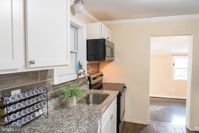 kitchen with light stone countertops, appliances with stainless steel finishes, ornamental molding, dark hardwood / wood-style floors, and white cabinetry