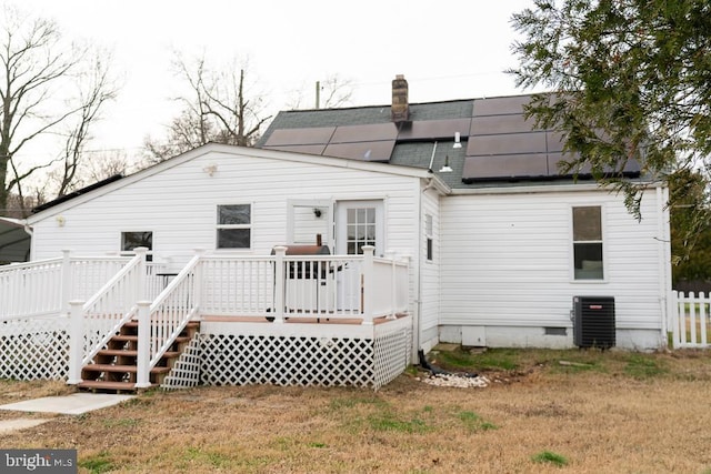 back of property with solar panels, central air condition unit, and a wooden deck