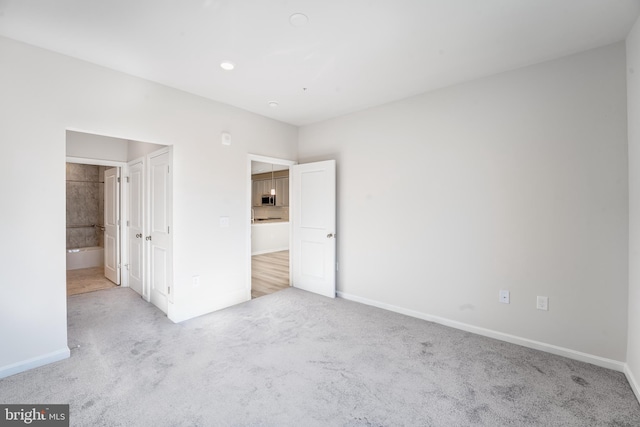 unfurnished bedroom featuring light colored carpet and connected bathroom