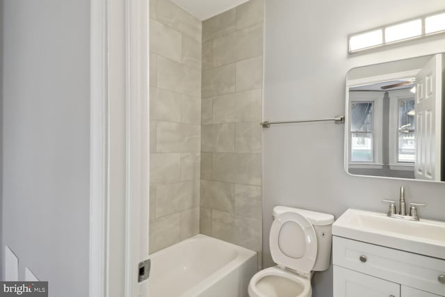 full bathroom with tiled shower / bath, ceiling fan, vanity, and toilet