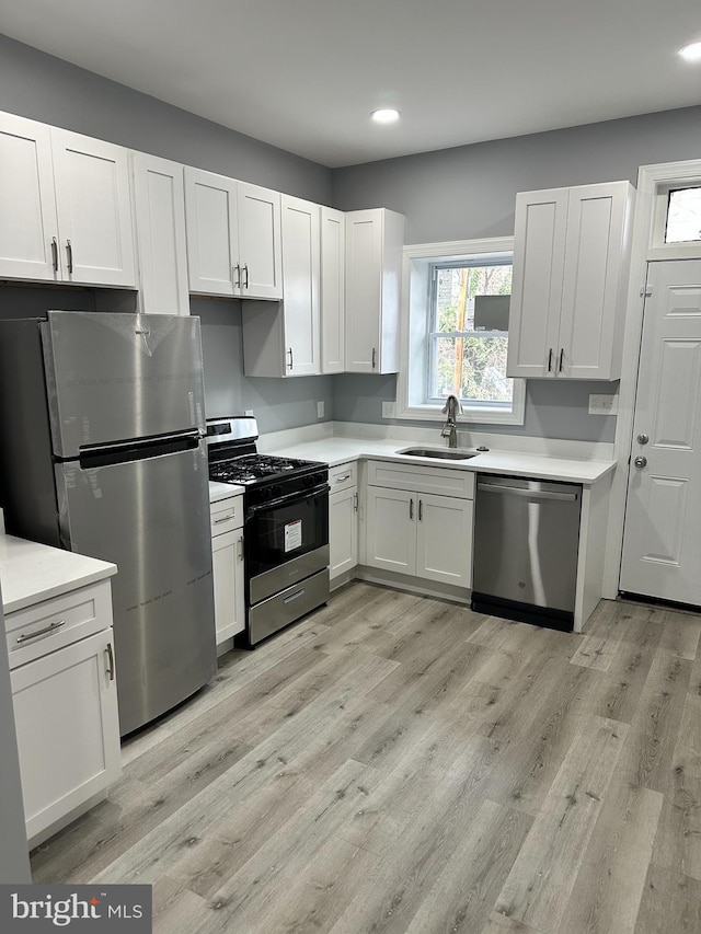 kitchen with light hardwood / wood-style flooring, stainless steel appliances, white cabinetry, and sink