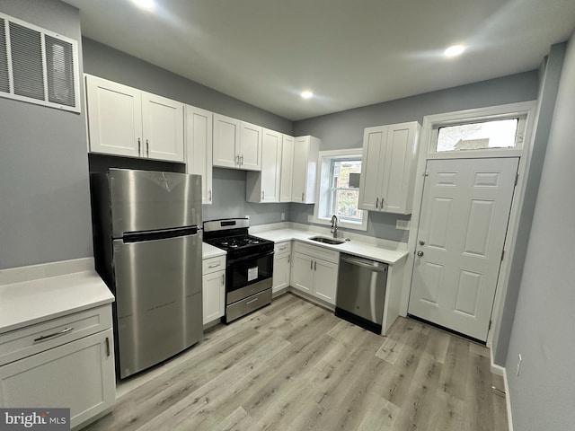 kitchen featuring white cabinetry, sink, appliances with stainless steel finishes, and light hardwood / wood-style flooring