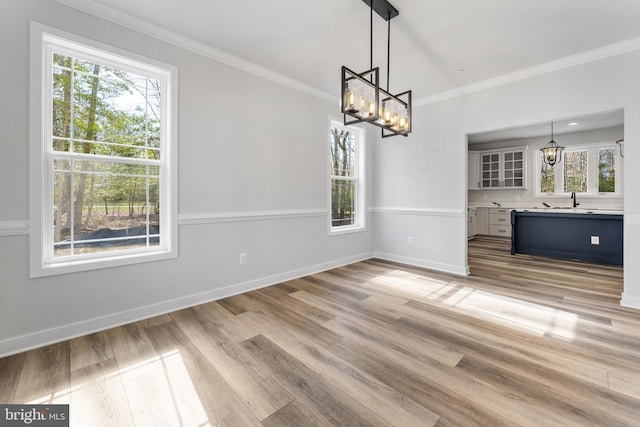 unfurnished living room with light wood-type flooring, a chandelier, and a wealth of natural light