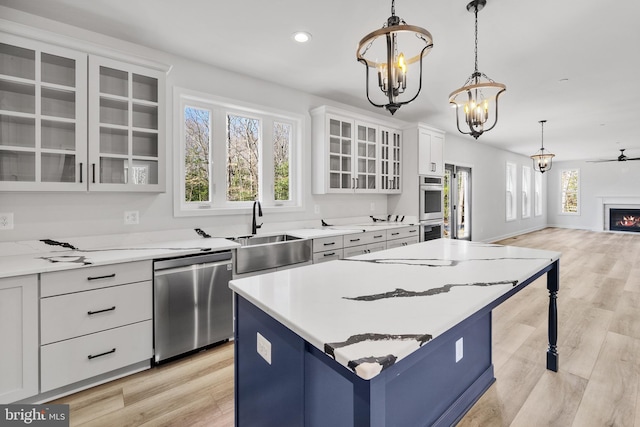 kitchen with a kitchen island, light hardwood / wood-style flooring, appliances with stainless steel finishes, white cabinets, and a healthy amount of sunlight