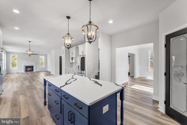 kitchen featuring a chandelier, pendant lighting, a breakfast bar, light hardwood / wood-style flooring, and white cabinets