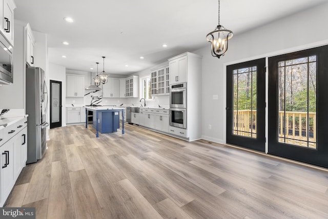 kitchen with a kitchen bar, decorative light fixtures, stainless steel appliances, and white cabinetry