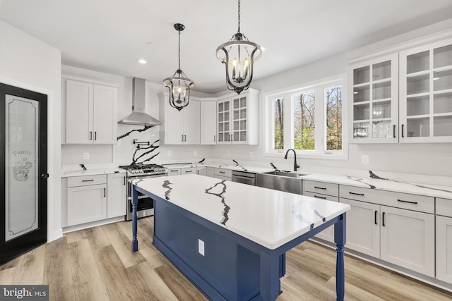 kitchen featuring white cabinetry, a kitchen breakfast bar, stainless steel appliances, light wood-type flooring, and wall chimney range hood