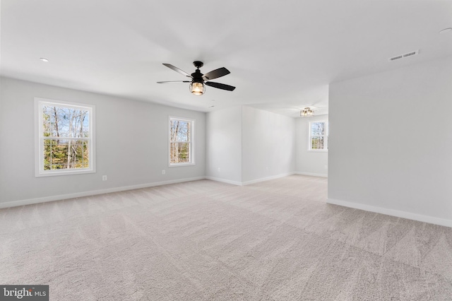 carpeted spare room with ceiling fan and a wealth of natural light