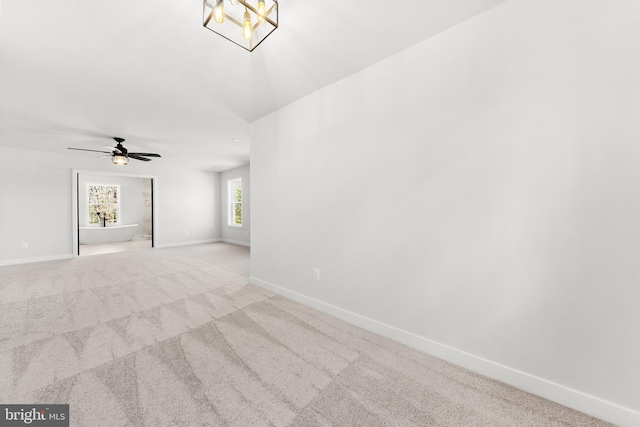 unfurnished room with ceiling fan with notable chandelier and light colored carpet