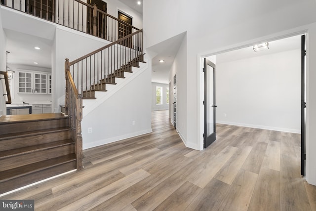 stairs with a high ceiling and light wood-type flooring