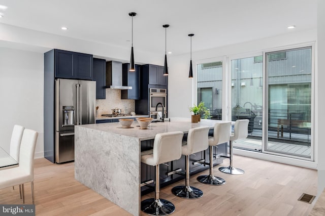 kitchen with light stone countertops, hanging light fixtures, plenty of natural light, a breakfast bar area, and appliances with stainless steel finishes