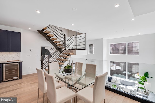 dining space with wine cooler and light hardwood / wood-style flooring