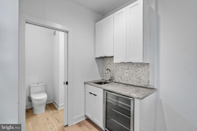 bar featuring light hardwood / wood-style floors, white cabinetry, sink, and beverage cooler