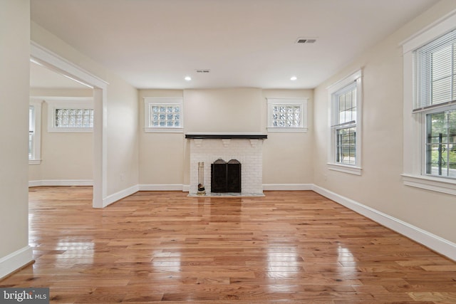 unfurnished living room with a brick fireplace and light hardwood / wood-style flooring