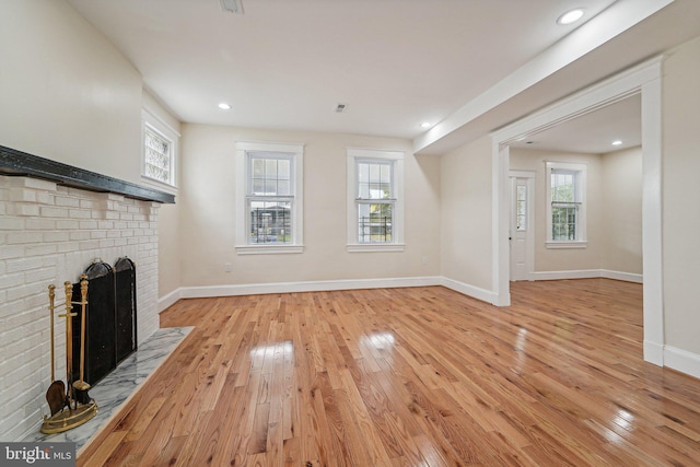 unfurnished living room featuring plenty of natural light, a fireplace, and light hardwood / wood-style floors