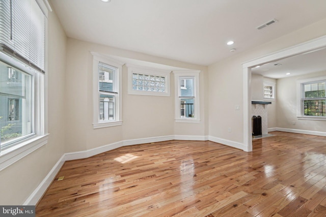 unfurnished living room with a fireplace, light hardwood / wood-style flooring, and a wealth of natural light