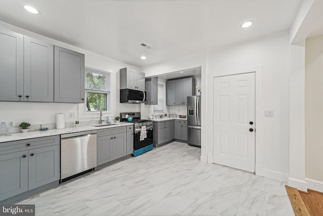 kitchen with appliances with stainless steel finishes, sink, and gray cabinetry