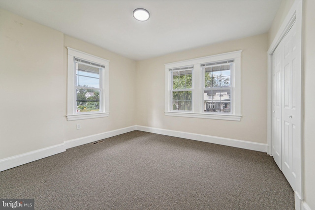 unfurnished bedroom with multiple windows, carpet floors, and a closet