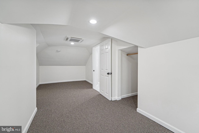 additional living space featuring vaulted ceiling and dark colored carpet