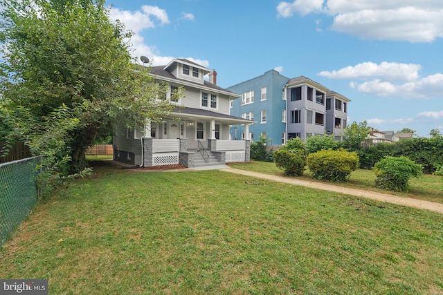 rear view of property featuring a yard and covered porch