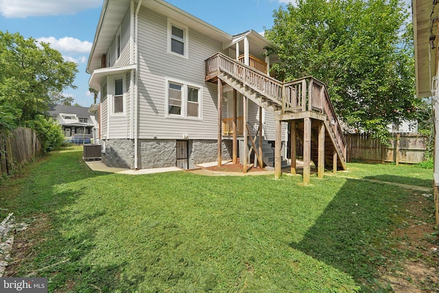 back of house with a wooden deck, a yard, and central AC