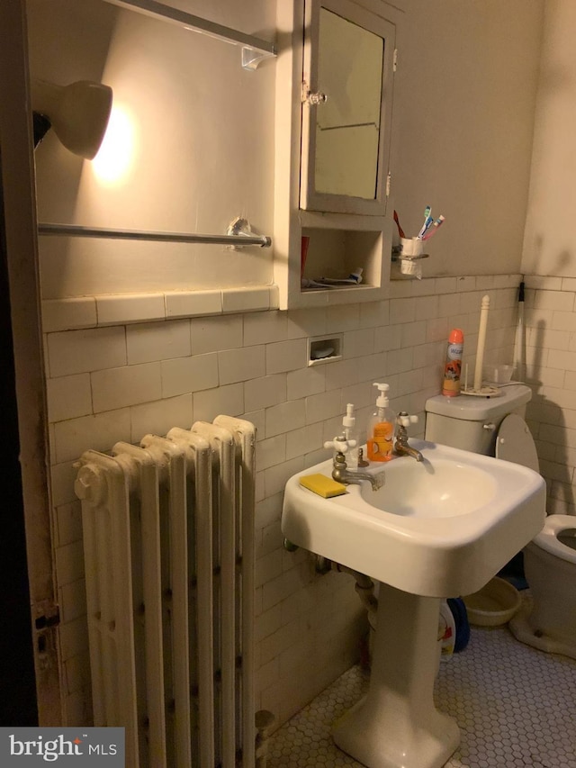 bathroom with radiator, tile patterned flooring, tile walls, and toilet