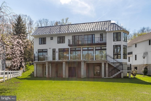 rear view of house with a sunroom, a balcony, and a yard