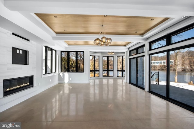 unfurnished living room featuring a healthy amount of sunlight, a water view, a tiled fireplace, and a tray ceiling