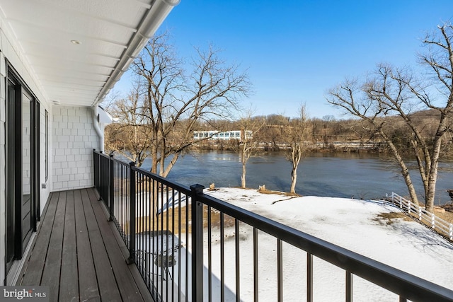 snow covered back of property featuring a water view