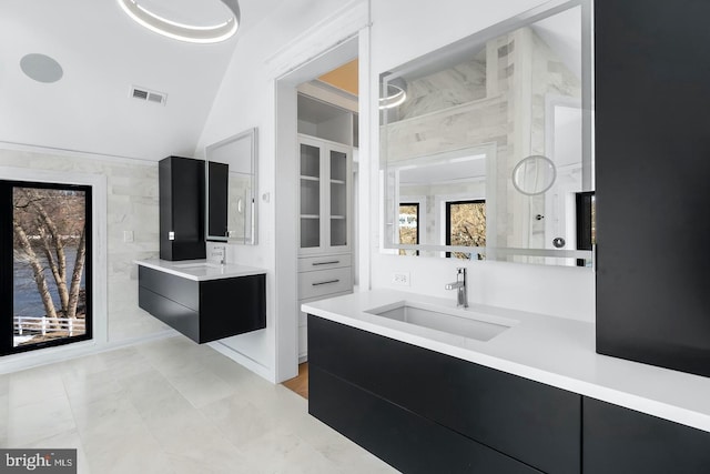 bathroom featuring tile walls, tile patterned flooring, vanity, and vaulted ceiling