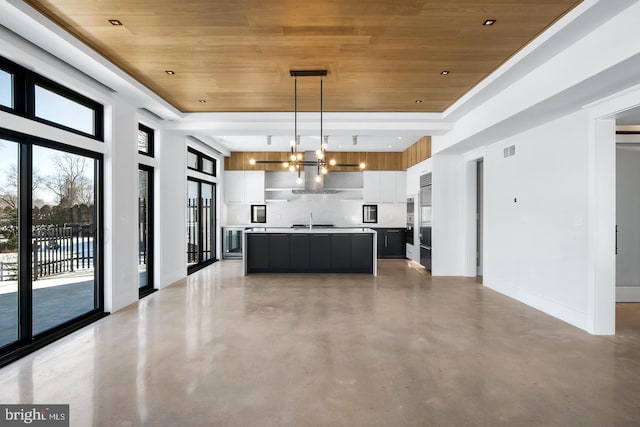 kitchen featuring tasteful backsplash, wood ceiling, sink, pendant lighting, and an island with sink