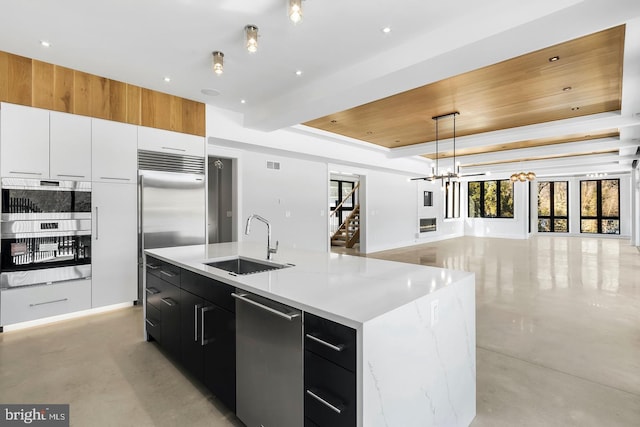 kitchen featuring pendant lighting, a raised ceiling, sink, appliances with stainless steel finishes, and a large island