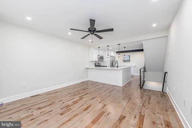 living room featuring ceiling fan, light wood-type flooring, and sink