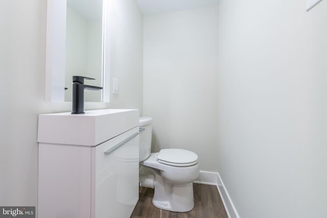 bathroom with wood-type flooring, vanity, and toilet